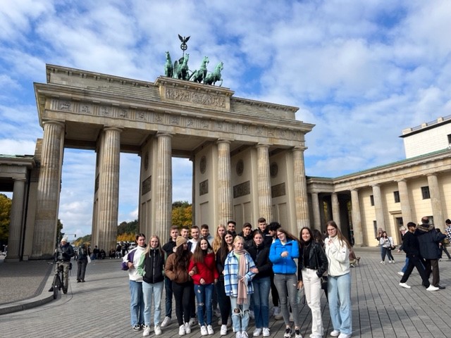 Gruppe von Schülern vor dem Brandenburger Tor in Berlin an einem sonnigen Tag.