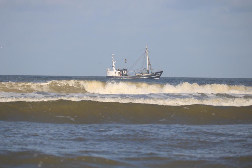 Ein Fischerei- oder Arbeitsboot auf dem Meer vor hohen Wellen.