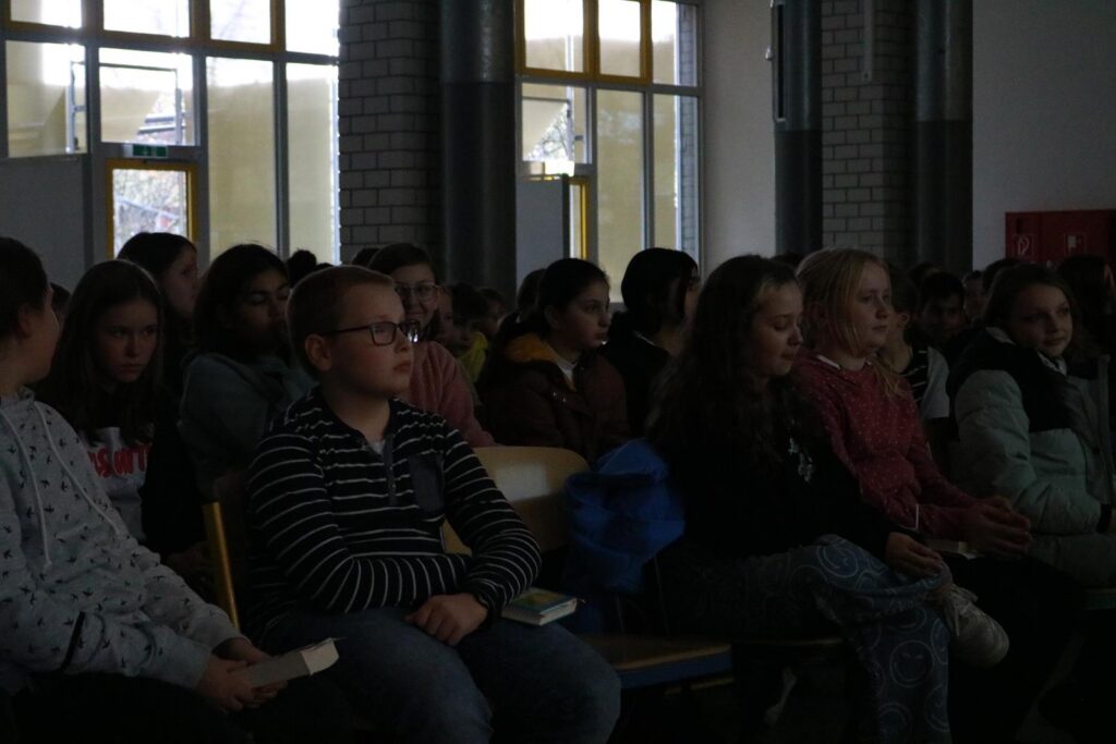 Schüler sitzen im Publikum bei einer Veranstaltung in einem Innenraum.