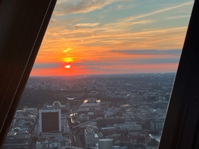 Sonnenuntergang über einer Stadtansicht mit Wolken und Gebäuden.
