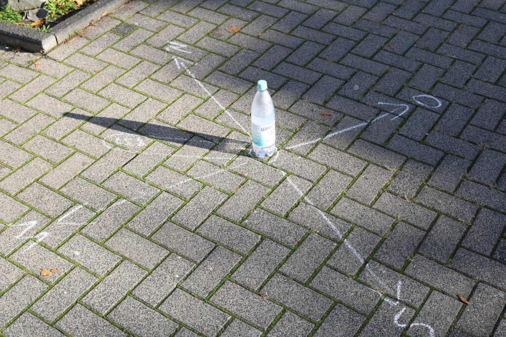 Wasserflasche steht in der Mitte eines mit Kreide gezeichneten Sterns auf dem Gehweg.