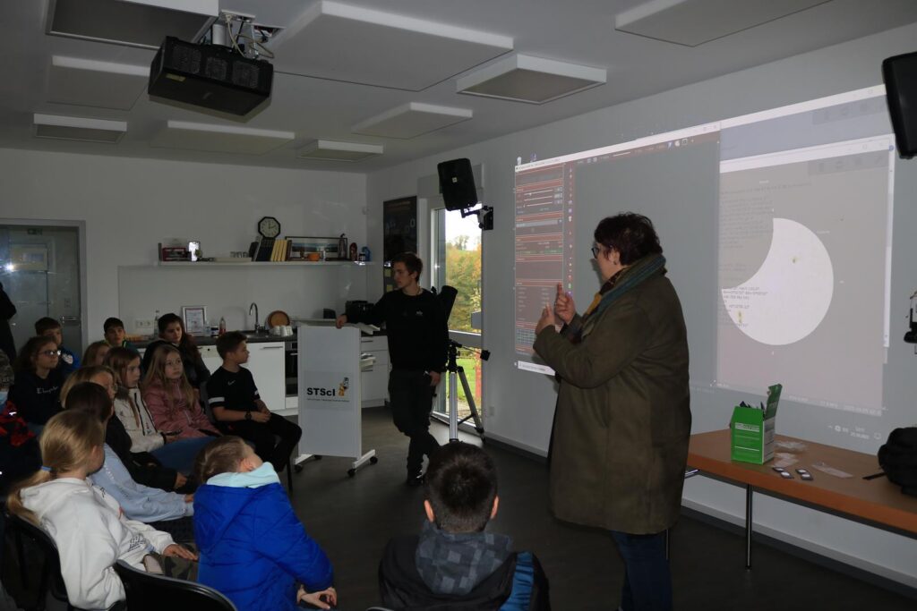 Schüler in einem Klassenzimmer verfolgen eine Präsentation von zwei Lehrkräften.