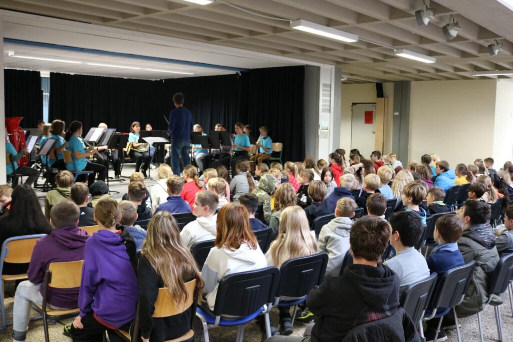 Schüler sehen eine Aufführung des Schulorchesters in der Aula.