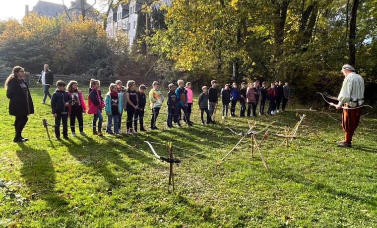 Gruppe von Schülern im Freien, beobachtet eine Person, die etwas demonstriert.