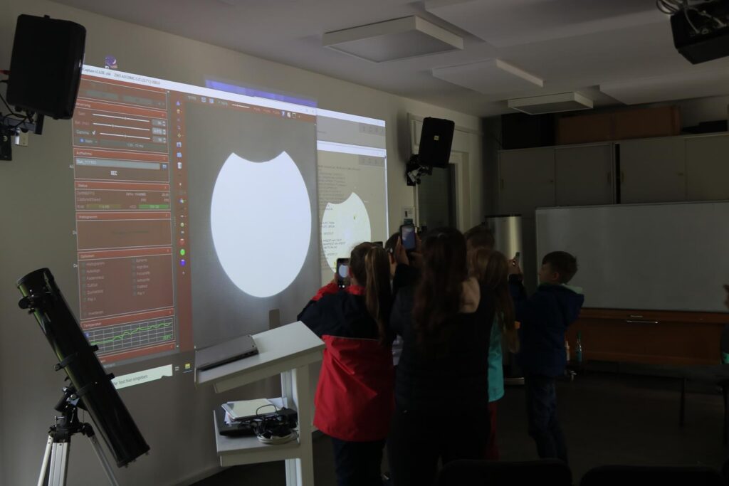 Schülerinnen und Schüler arbeiten an einem Projekt vor einer digitalen Präsentation.