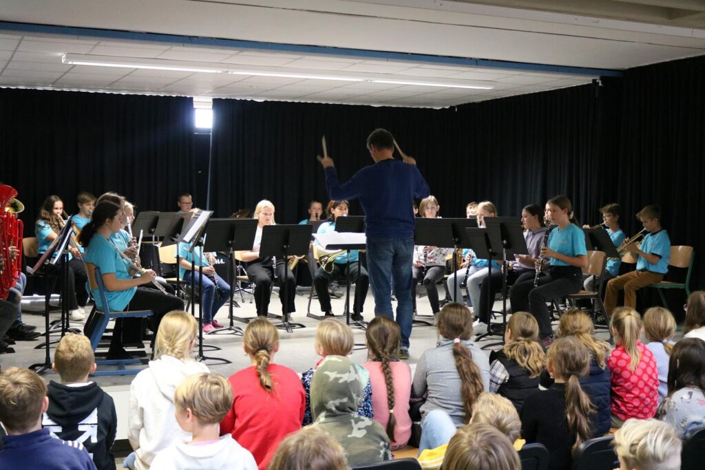 Schülerinnen und Schüler spielen in einem Orchester vor Publikum.