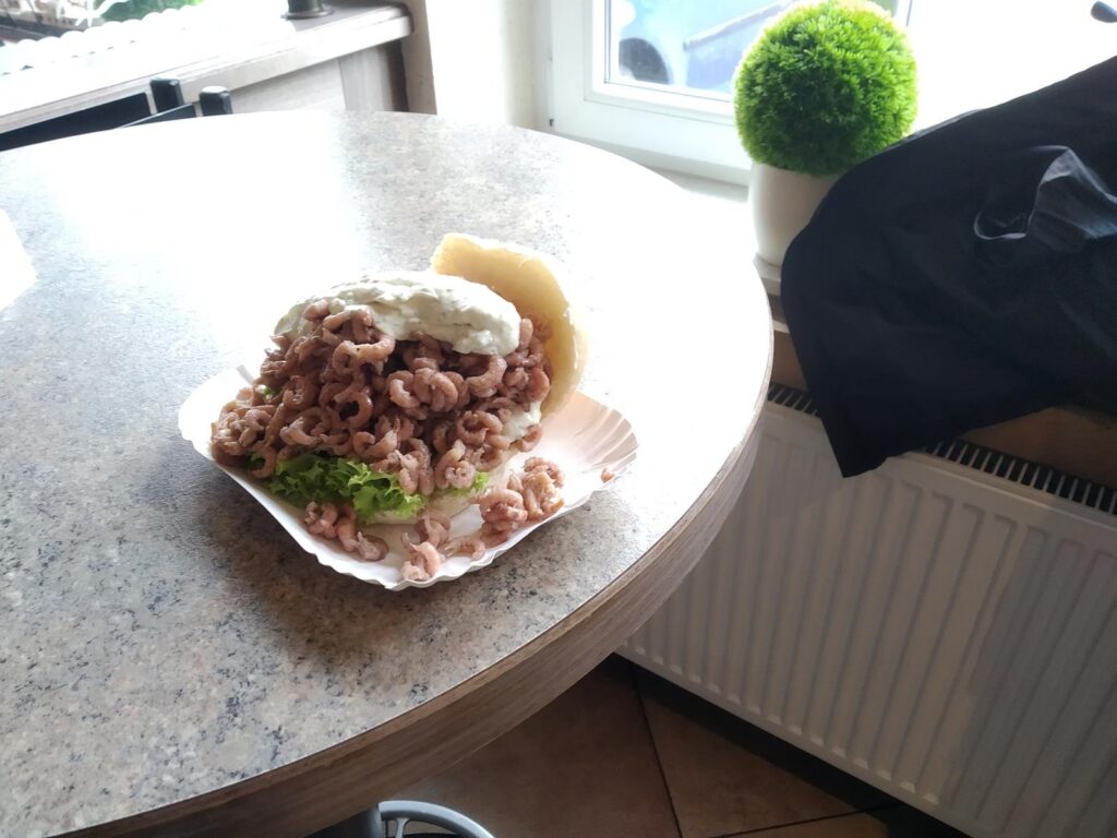 Ein großer Burger mit gefülltem Brötchen und Salat auf einem Tisch.
