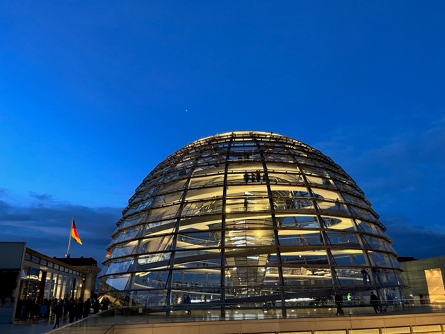Reichstagsgebäude mit gläserner Kuppel bei Dämmerung.