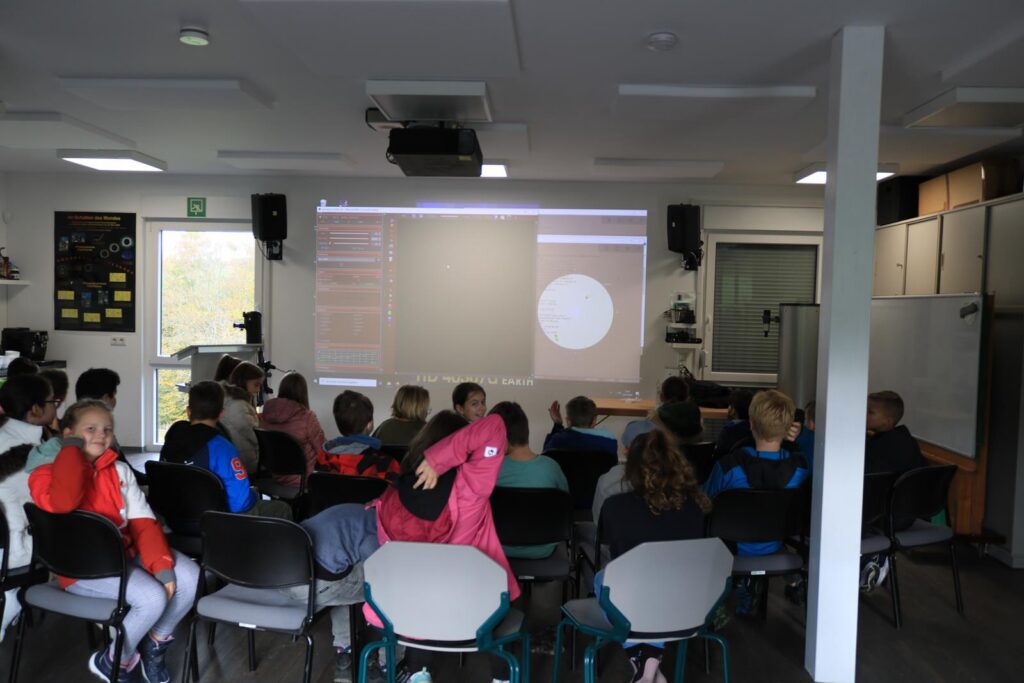 Schüler sitzen im Klassenraum und schauen auf eine Präsentation.