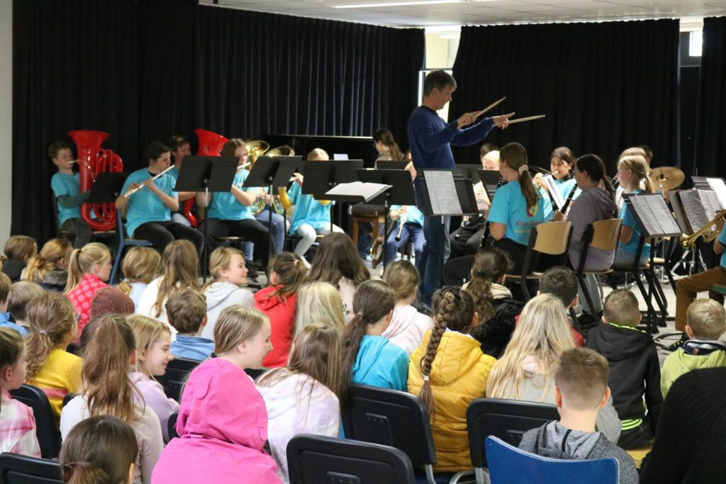 Schüler bei einem Konzert, Musiker auf der Bühne, Publikum im Vordergrund.