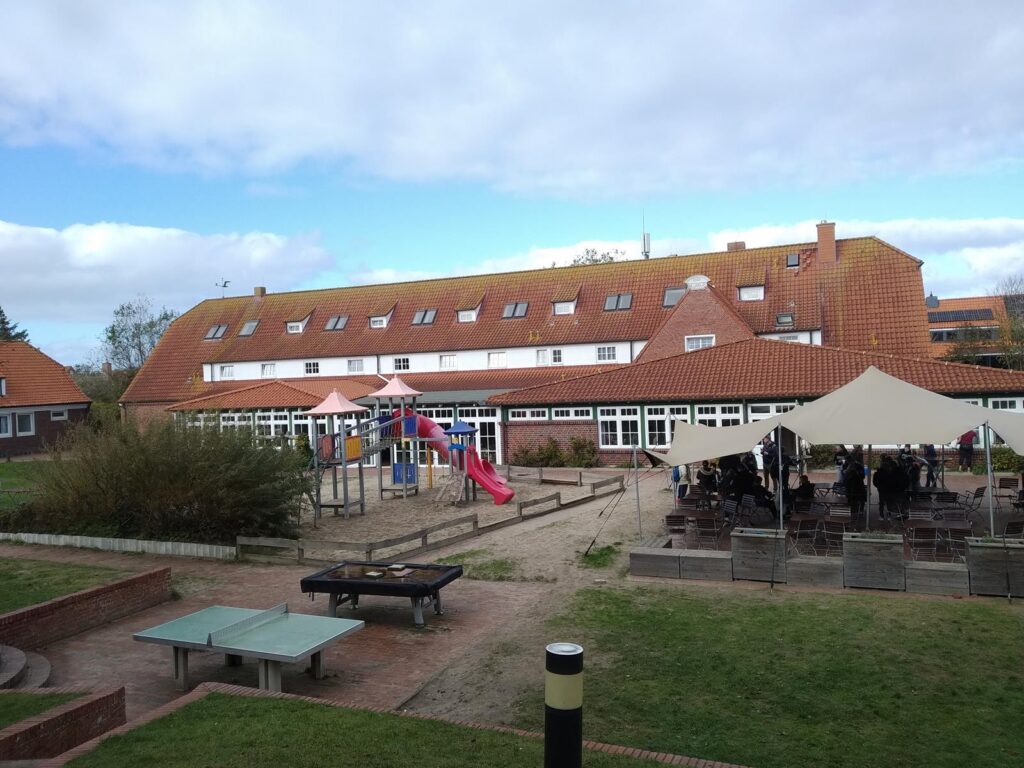 Schulgebäude mit Spielplatz und überdachter Sitzgelegenheit.