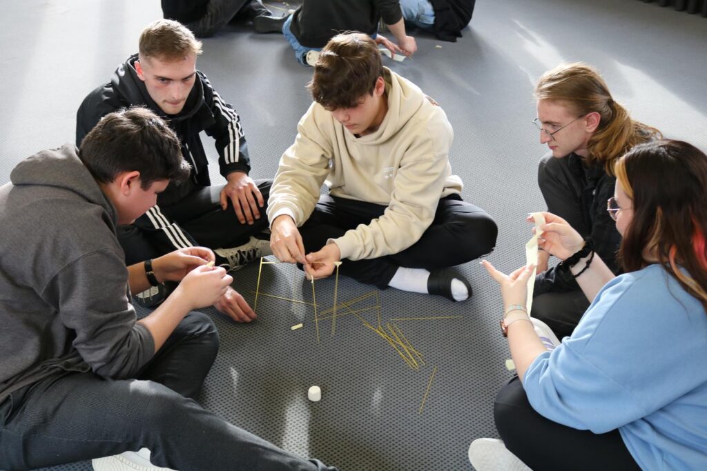 Schüler arbeiten zusammen und bauen mit Spaghetti und Marshmallows.