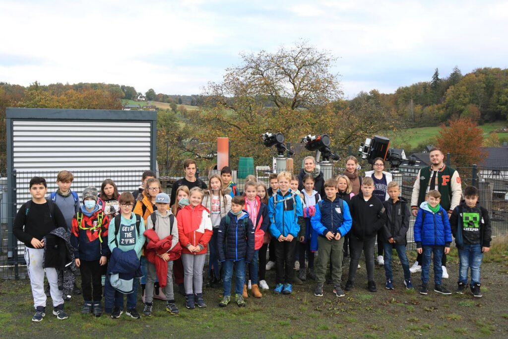 Eine Gruppe von Kindern und Erwachsenen steht auf einem Bauernhof.