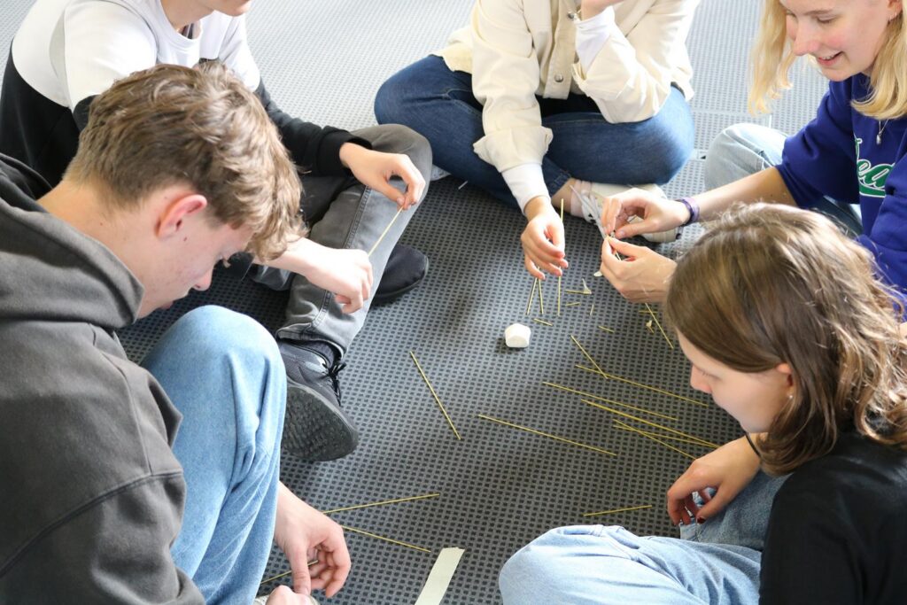 Schüler arbeiten gemeinsam am Boden an einem Projekt mit Materialien.