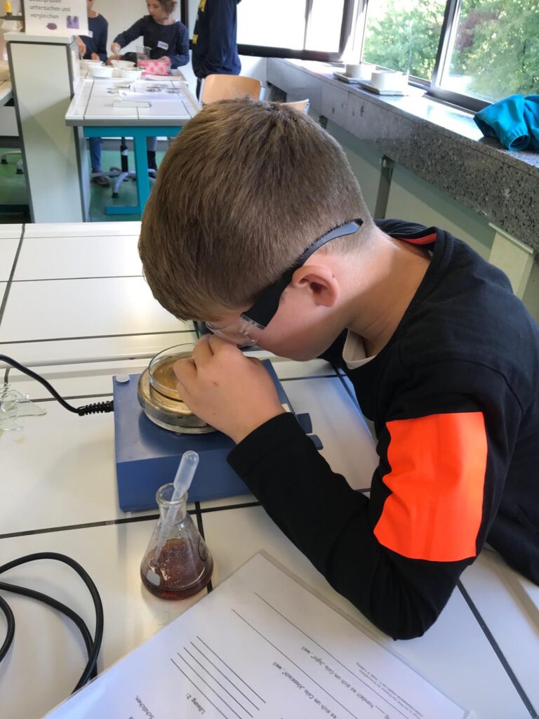 Schüler beobachtet ein Experiment unter einem Mikroskop in einem Labor.