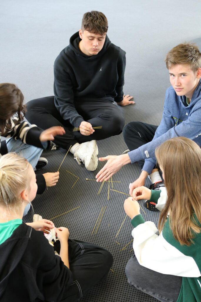 Schüler sitzen im Kreis und arbeiten gemeinsam mit Stäbchen.