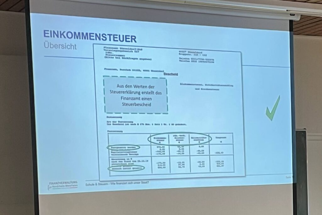 Präsentation über Einkommenssteuer mit einer Steuererklärung auf einem Bildschirm.