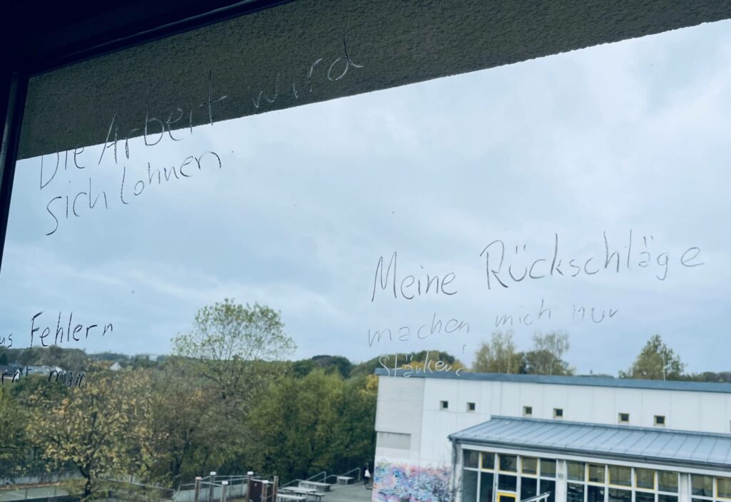 Fenster mit beschrifteter Oberfläche und Aussicht auf den Schulhof.