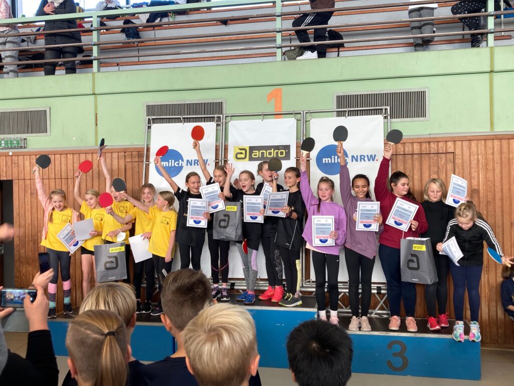 Gruppe von Kindern auf dem Siegerpodium mit Urkunden und Medaillen.