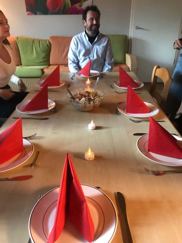 Ein gedeckter Tisch mit roten Servietten, Kerzen und einem Obstschalen-Mittelpunkt.