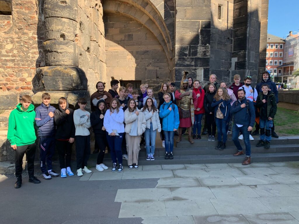 Gruppe von Schülern und Lehrern vor einer historischen Gebäude-Fassade.