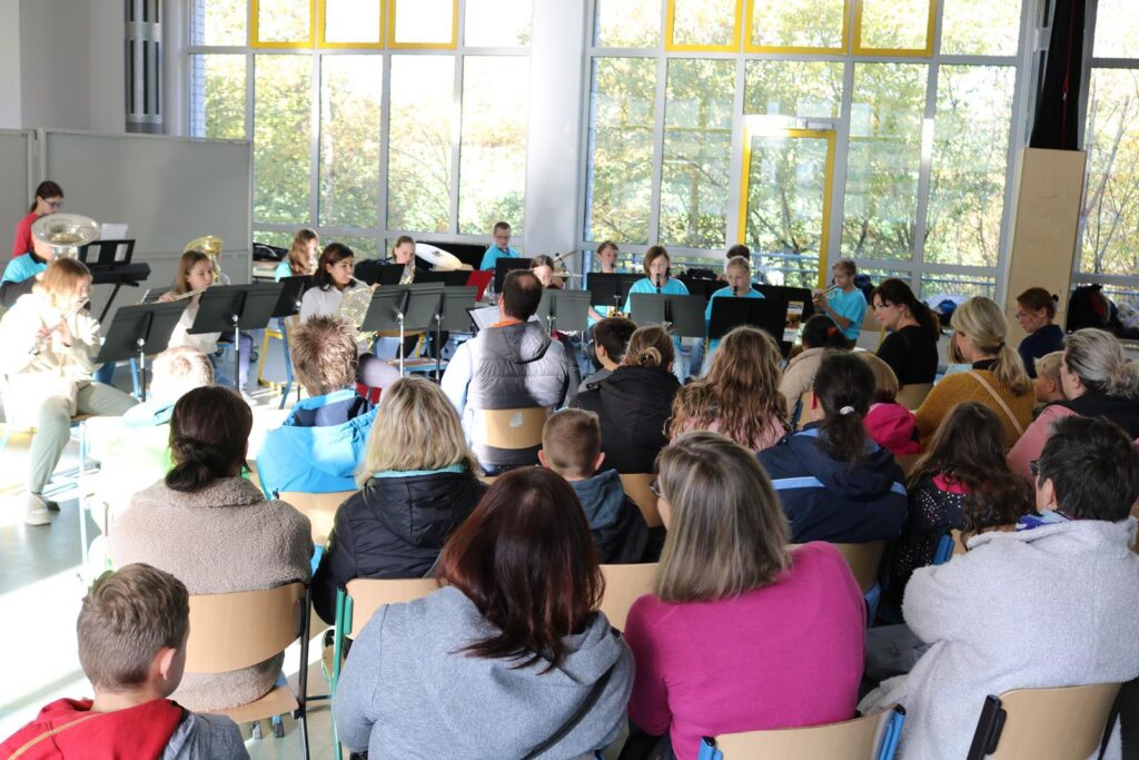 Schüler spielen ein Konzert vor Publikum in einem hellen Raum.