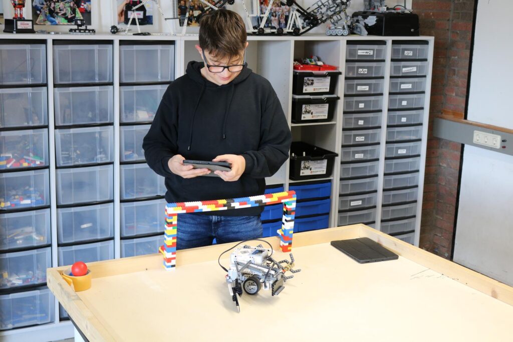 Schüler steuert einen Roboter mit einem Tablet in einem Klassenraum.