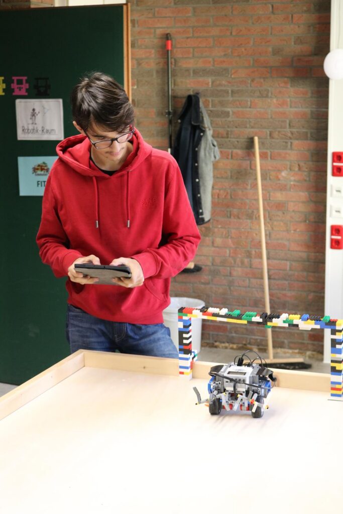 Schüler programmiert einen Roboter an einem Tisch mit Bauklötzen.