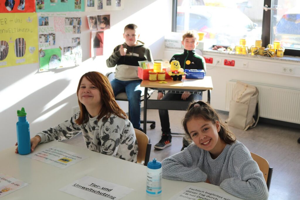 Schülerinnen und Schüler sitzen in einem Klassenraum an Tischen.