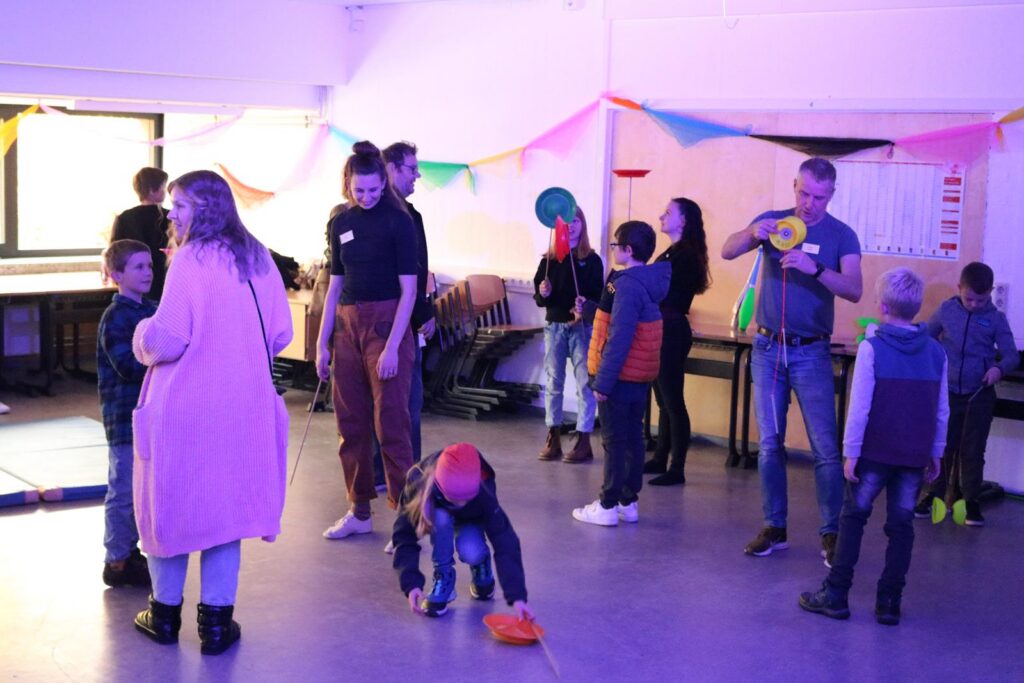 Kinder und Erwachsene stehen in einem festlich dekorierten Raum beim Spielen.