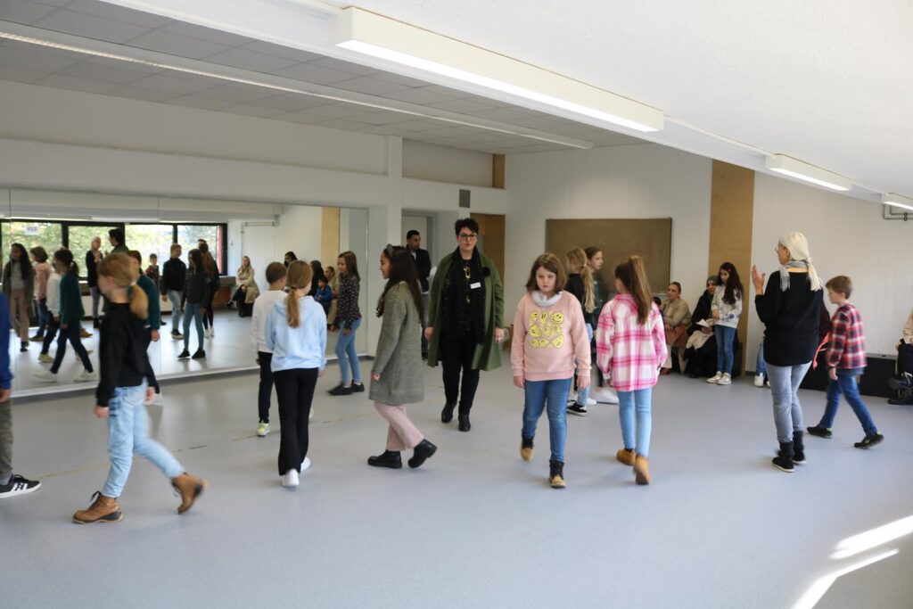 Schülerinnen und Schüler laufen in einem großen Raum mit Spiegeln.