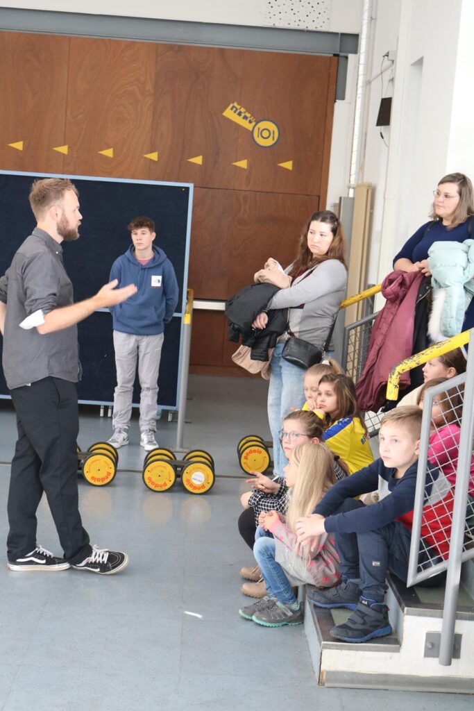 Gruppendiskussion mit Kindern und Erwachsenen in einem Raum.