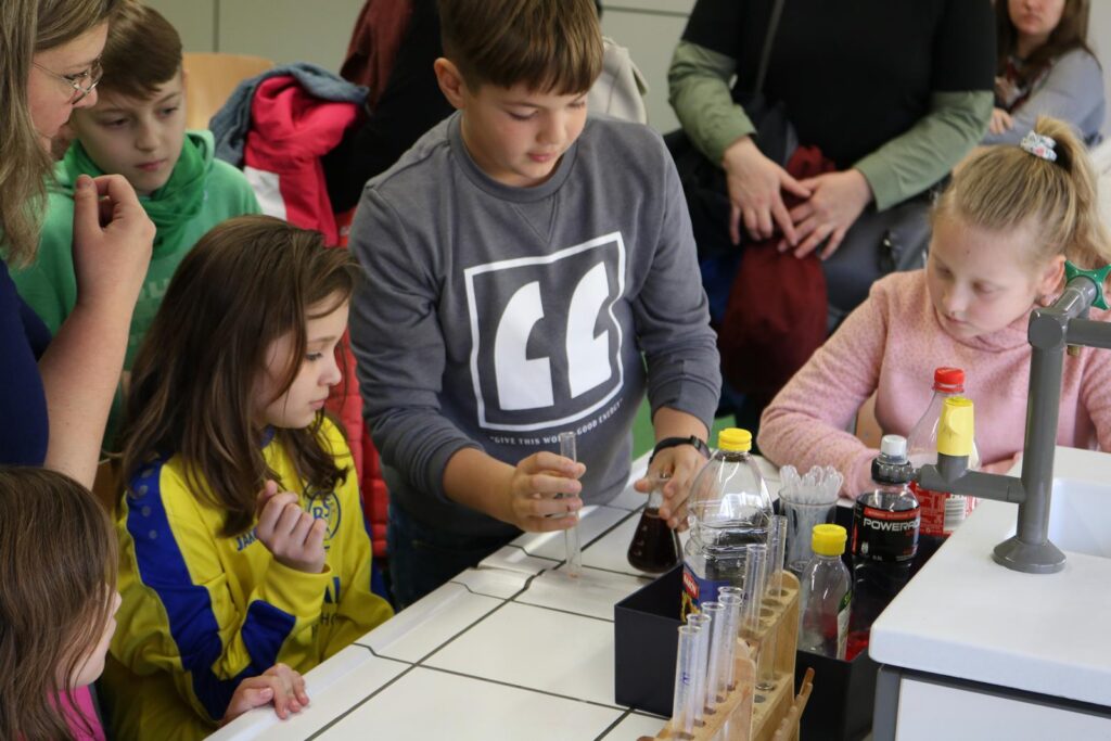 Kinder experimentieren an einem Tisch mit verschiedenen Chemikalien und Werkzeugen.