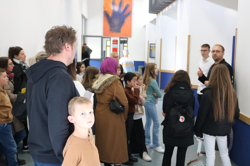 Gruppengespräch in einem Schulflur mit Schülern und Erwachsenen.