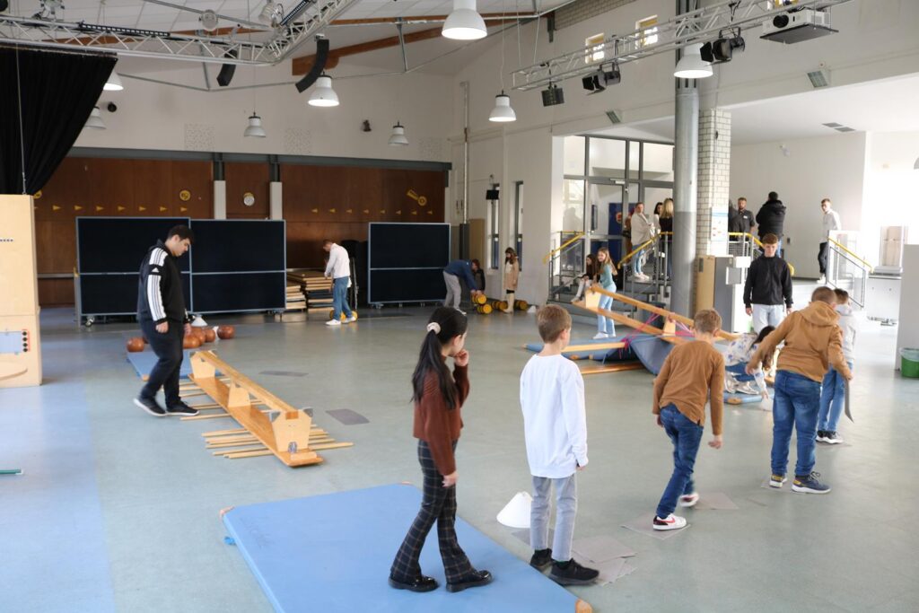 Schülerinnen und Schüler nutzen einen Bewegungsraum mit verschiedenen Geräten.