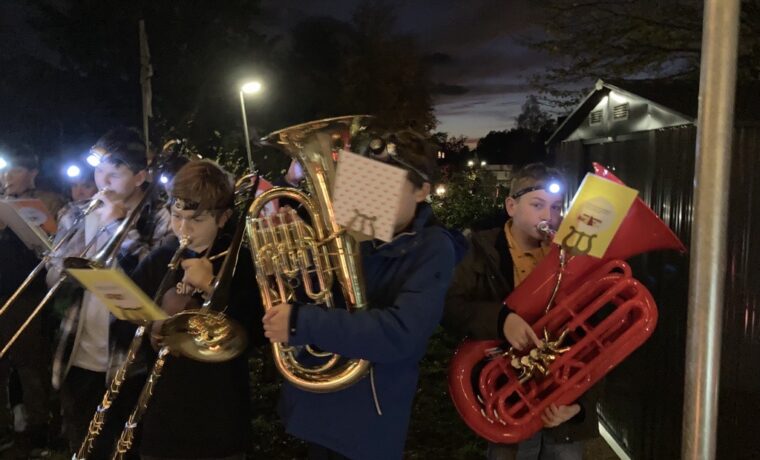 Schüler spielen Blasinstrumente bei Nacht, umgeben von Laternenlicht.