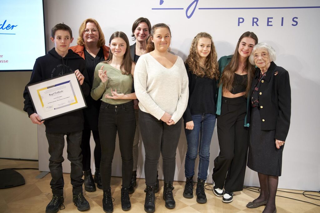 Gruppe von sieben Personen steht für ein Foto, eine Person hält eine Urkunde.