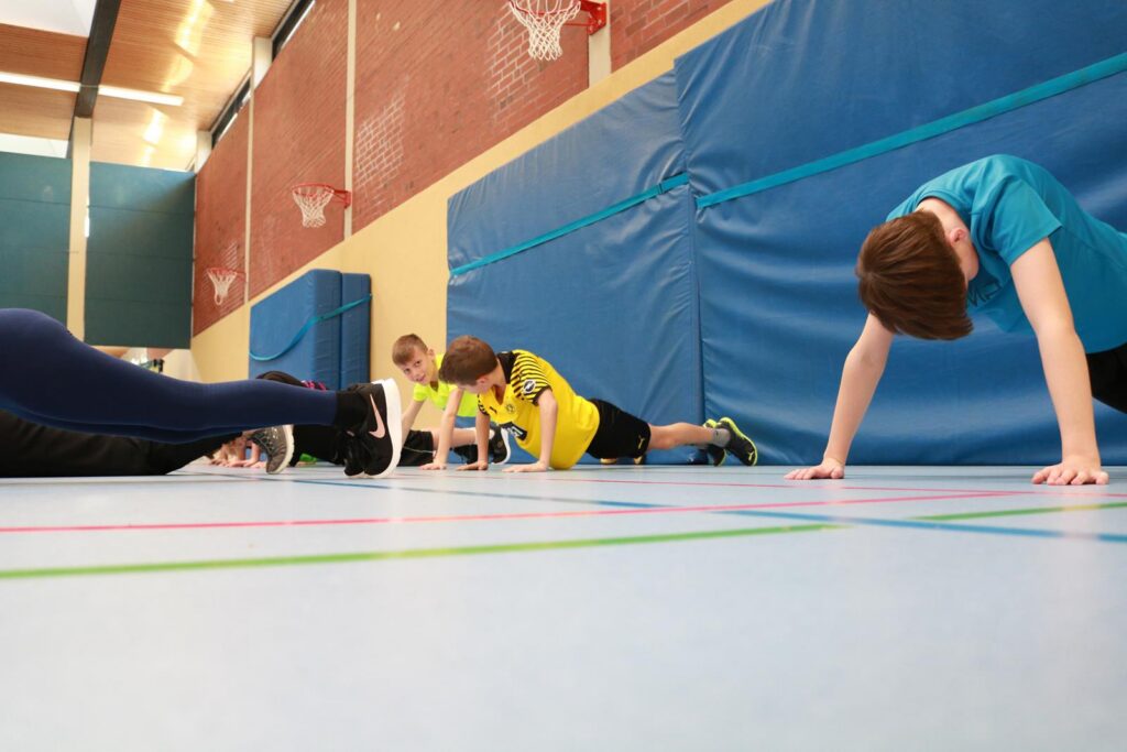 Schüler:innen machen Liegestütze in einer Turnhalle.