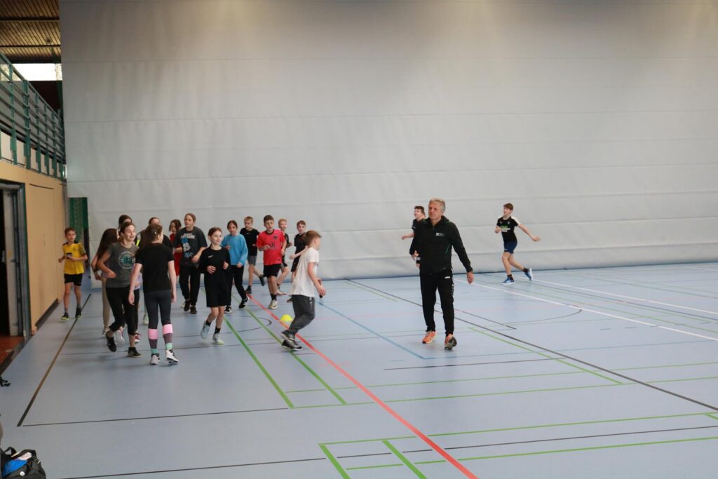 Schülerinnen und Schüler beim Sporttraining in einer Halle.