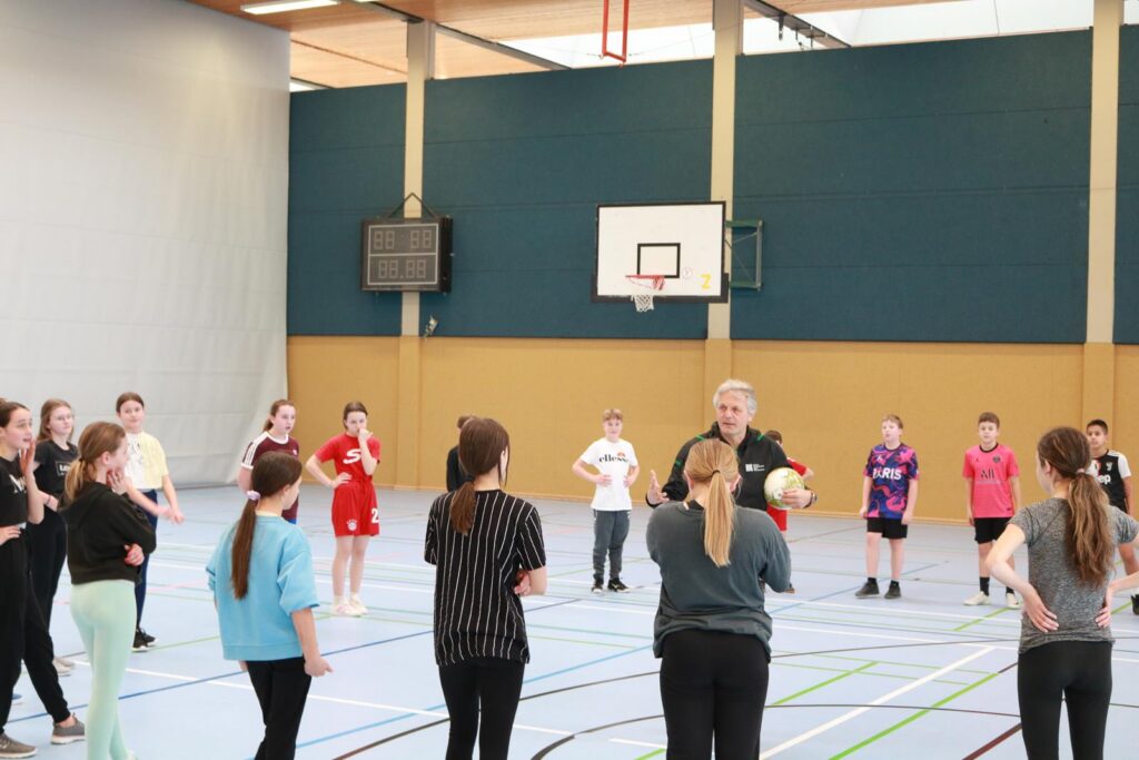 Gruppentraining in einer Sporthalle mit Jugendlichen und einem Trainer.