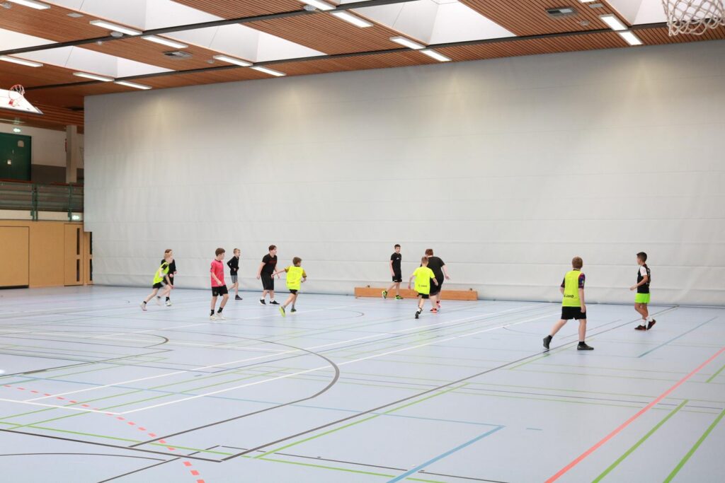 Sporthalle mit Jugendlichen, die Fußball spielen.