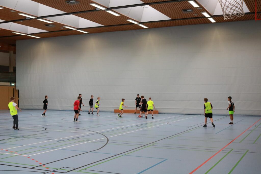 Sporthalle mit mehreren Spielern beim Volleyballtraining.