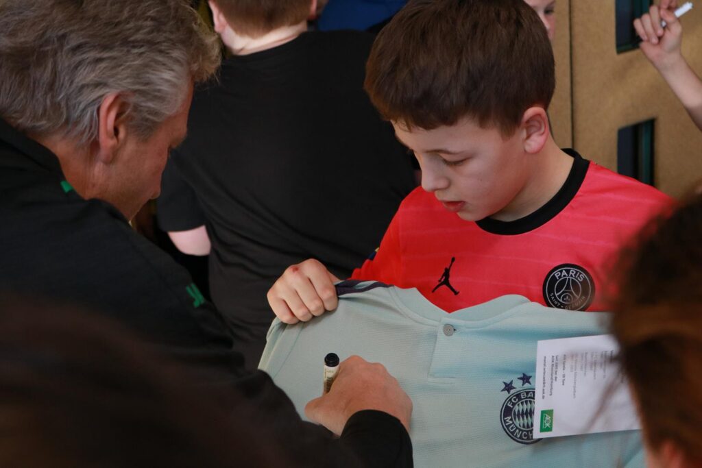 Junge mit einem Fußballtrikot erhält eine Unterschrift.