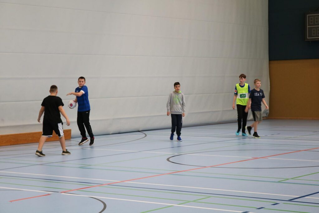 Schüler spielen in der Sporthalle Basketball.