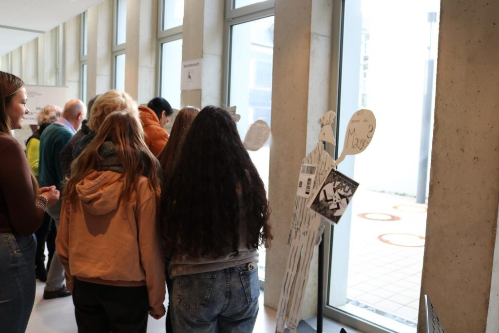 Gruppe von Schülerinnen und Schülern steht vor einer Ausstellung mit Figuren.
