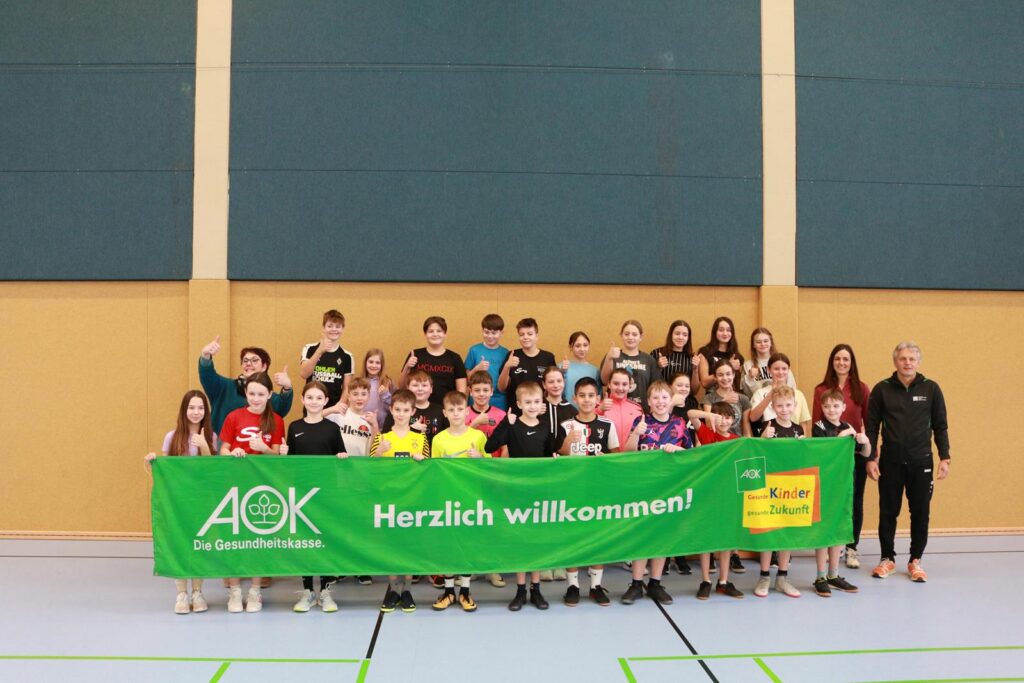 Grupp Foto von Schülern mit einem Banner in einer Sporthalle.