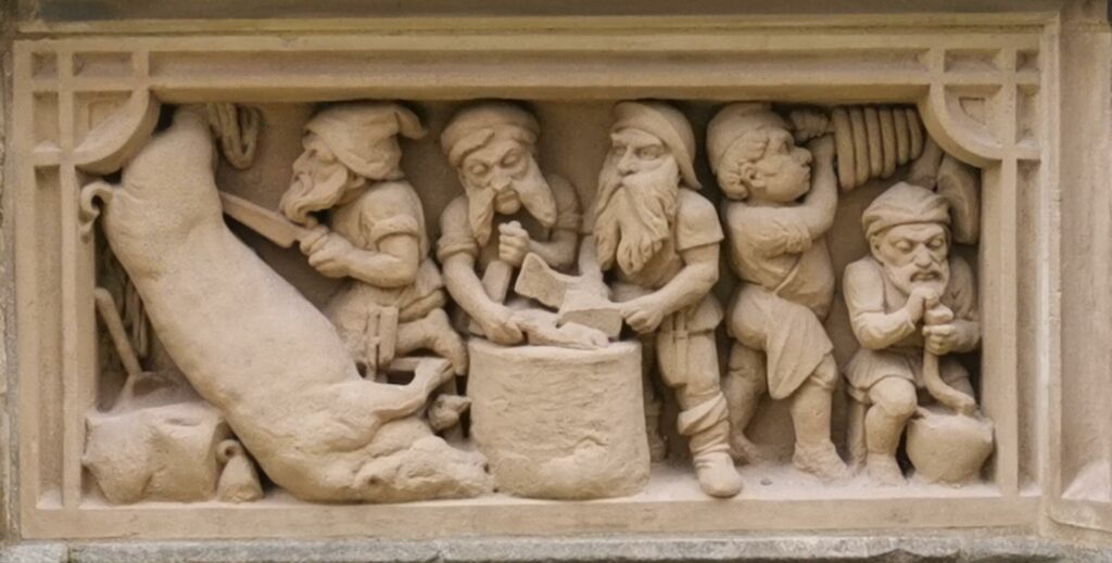Relief mit mehreren Figuren, die eine Schweinehälfte bearbeiten.