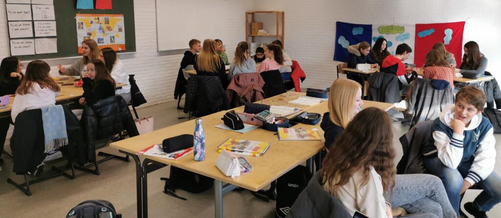 Schülerinnen und Schüler arbeiten in Gruppen in einem Klassenzimmer.