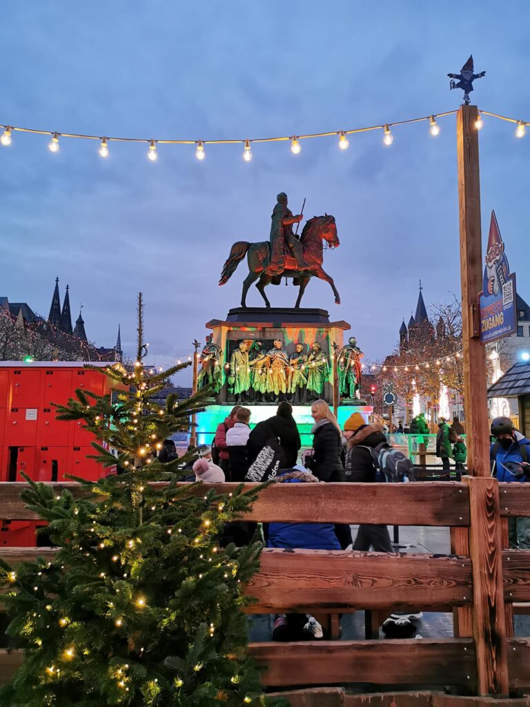 Weihnachtsmarkt mit einem Statue auf dem Pferd und festlicher Beleuchtung.