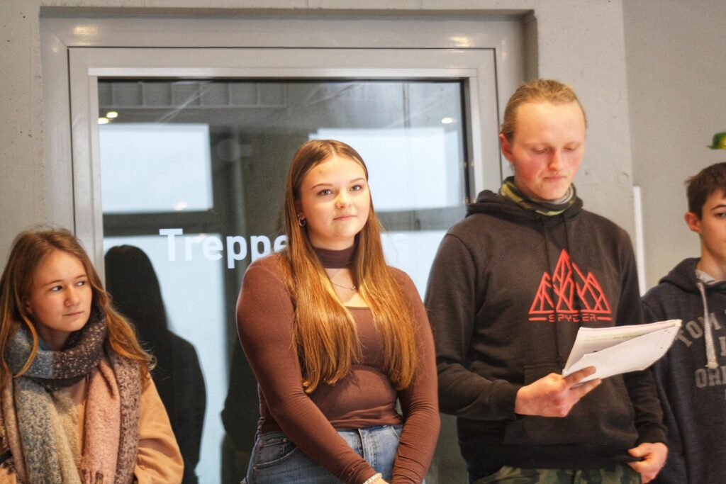 Schüler präsentieren in einer Schule vor einer Gruppe von Zuhörern.